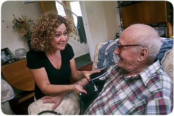 Female carer taking a patient's blood pressure at home